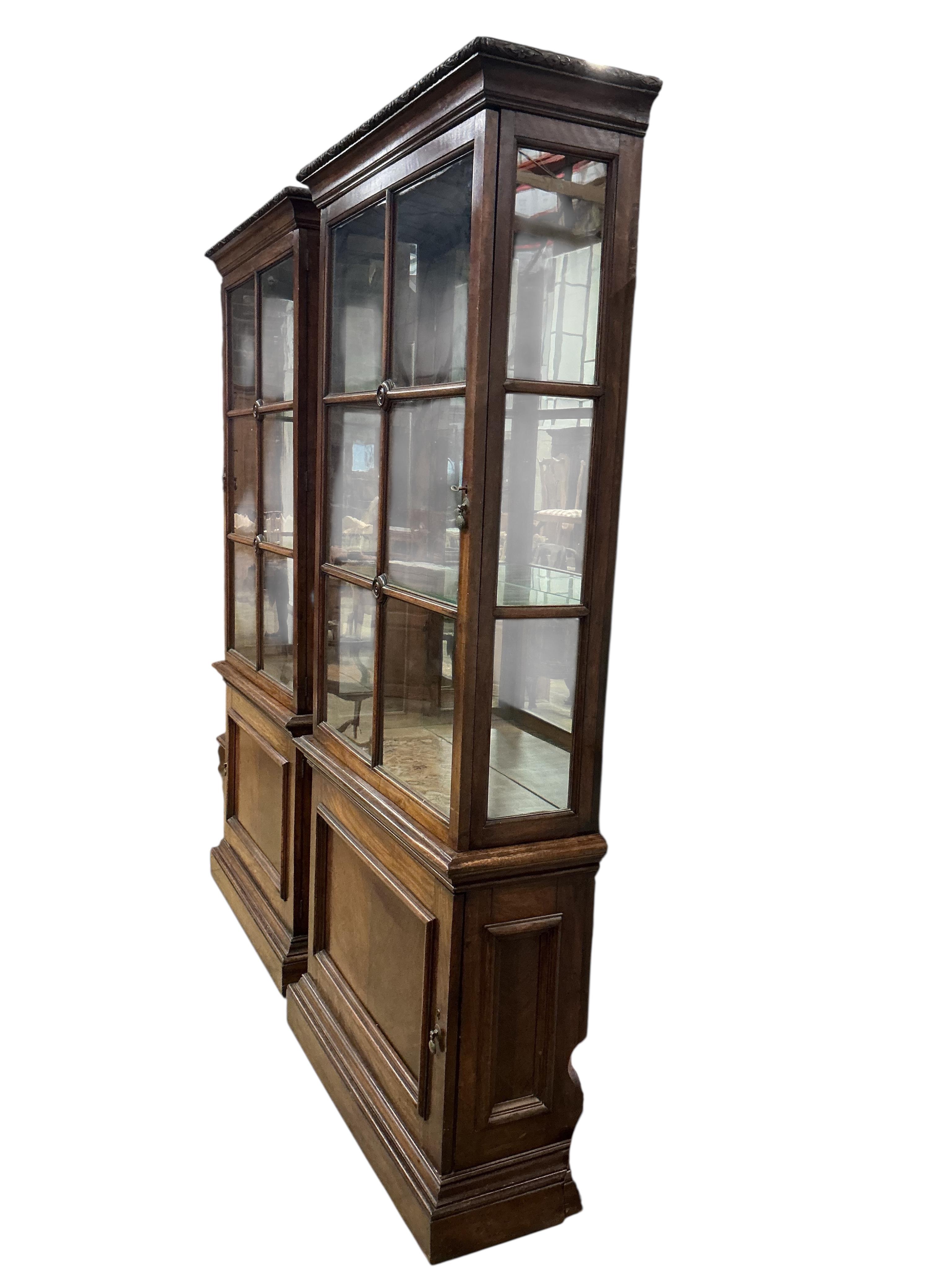 A pair of 1930's walnut vitrines, with single bar glazed doors over single panelled doors, on plinth feet, width 94cm, depth 35cm, height 212cm